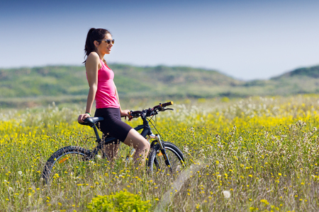 Spring portrait of Fit woman riding mountain bike in the countrysideの写真素材