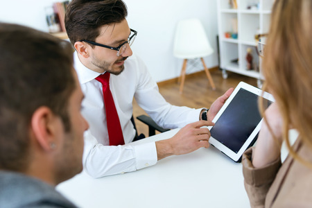 Portrait of business young man explaining terms of contract to his clients in the office.の写真素材