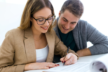 Portrait of beautiful young couple signing financial contract in the office.