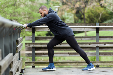 Portrait of fit and sporty young man doing stretching in the city.