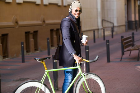 Portrait of handsome young man walking with his bike in the street.の写真素材