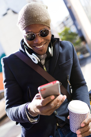 Portrait of handsome young man using his mobile phone in the street.の写真素材