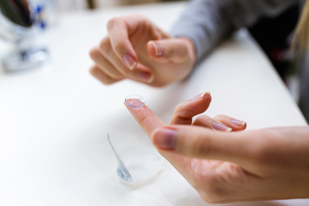 Close-up of hand's of young woman holding one contact lenses before putting on them.の写真素材