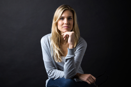 Portrait of confident young woman looking at camera over black background.の写真素材