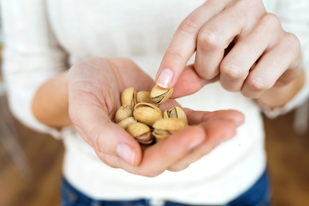 Young woman hands holding and picking up a pistachios nuts at home.の写真素材