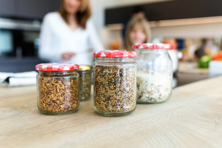 Close-up various uncooked cereals, grains, beans and rice for healthy cooking in glass jars on...