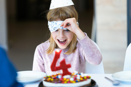 Shot of funny little girl surprised and having fun with birthday cake in the kitchen at home.の写真素材