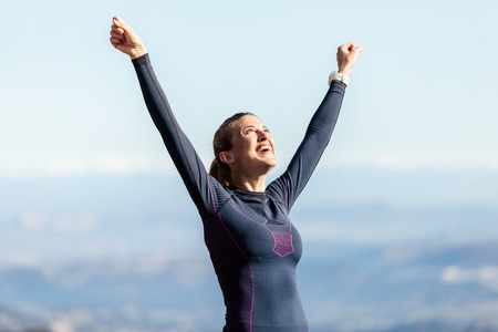 Shot of trail runner with open arms raised while enjoying nature on mountain peak.の写真素材