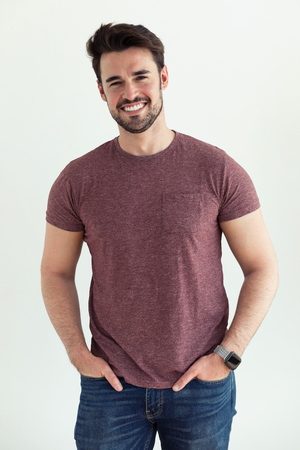 Portrait of handsome young man smiling and looking at camera over white background.の写真素材
