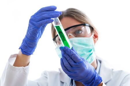 Close-up of young scientist woman with protective glasses looking test tube on white background.の写真素材