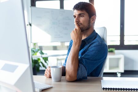Shot of software developer thinking in new project while working with computer in the modern startup...