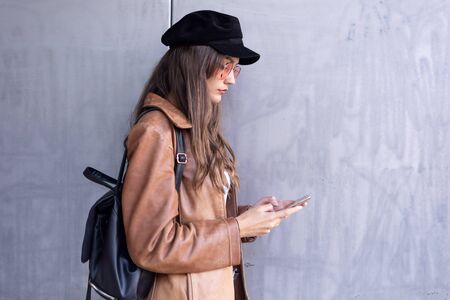 Shot of pretty young woman using her mobile phone while standing in the street.の写真素材