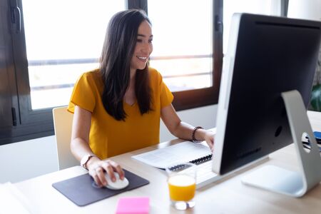 Shot of smiling young businesswoman working with her computer in the office.の写真素材