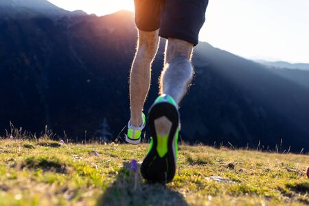 Close-up of muscular legs of the athlete runner from behind during the racing race in the mountain trail.の写真素材