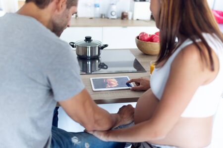 Shot of pretty young pregnant couple looking at their baby's ultrasound on the digital tablet in the...