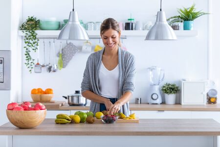 Shot of pretty young woman preparing fruit drink in the kitchen at home.の写真素材