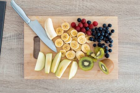 Shot of different pieces of fresh fruits on a wooden board for cutting. Healthy food concept.