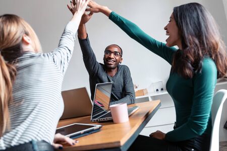 Shot of group of successful young businesspeople holding up their right hands on coworking place.の写真素材