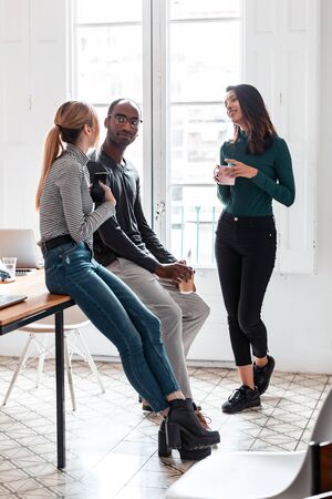 Shot of three young business people drinking coffee while taking a break in the office.の写真素材
