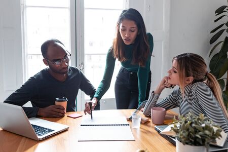 Shot of pretty young entrepreneur woman explaining a project to his colleagues on coworking place.の写真素材