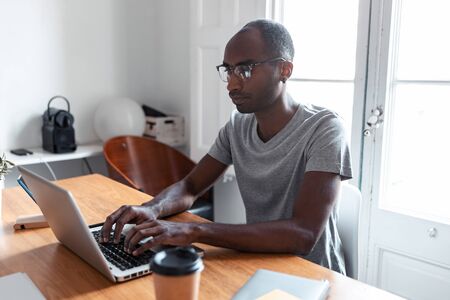 Shot of concentrated young black business man working with laptop in the office.の写真素材