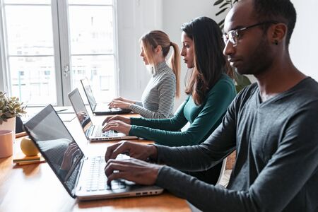 Shot of line of concentrated employees working with laptops on coworking place.の写真素材
