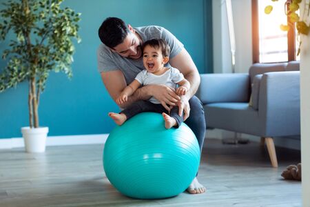 Shot of handsome young father with his baby playing together and having fun with the ball at home.の写真素材