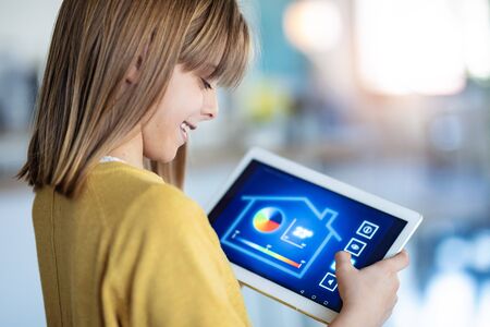 Shot of little girl using a domotic system with her digital tablet while standing at home.の写真素材