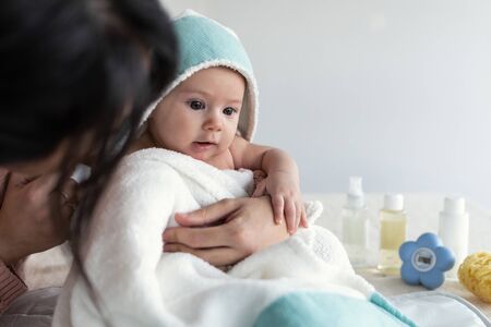Shot of young mother holding cute baby in towel after bathing at home.の写真素材