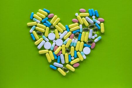Shot of heart made of colorful pills on green background. Healthcare concept.の写真素材