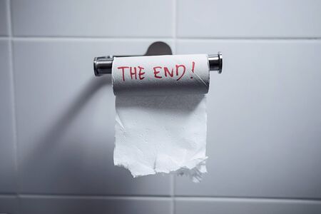 Close-up of finished toilet paper roll in the bathroom. The end is written in red on the roll.の写真素材