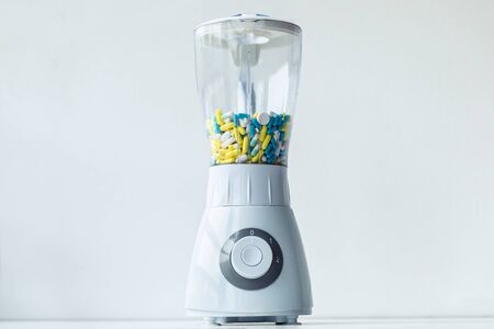 Shot of a white blender with multicolored capsules and pills. Nutritional supplementation concept.の写真素材