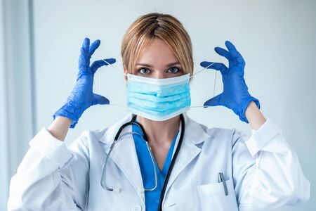 Shot of female doctor wearing hygienic face surgical medical mask to prevent infection, respiratory...
