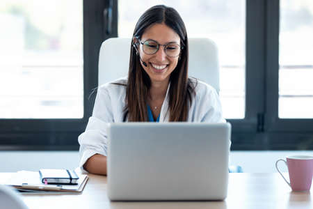 Shot of female doctor talking with colleagues through a video call with a laptop in the...