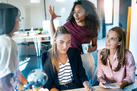 Shot of four smart businesswomen talking and reviewing the latest work done on the computer in a joint workspace.の写真素材