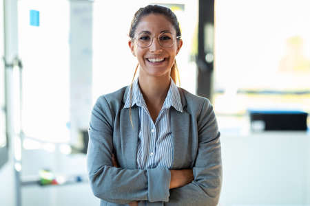 Shot of smiling young businesswoman looking at camera while standing in the office.の写真素材