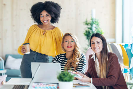 Shot of casual multiethnic business women working with laptops while talking of they new projects together in coworking place.の写真素材