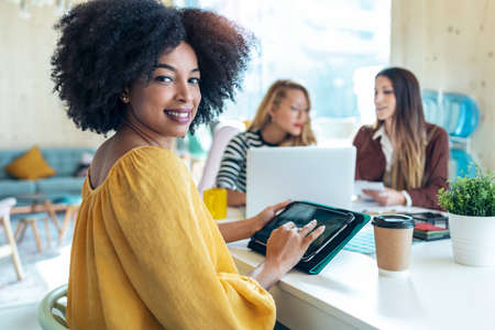Shot of casual multiethnic business women working with laptops while talking of they new projects together in coworking place.の写真素材