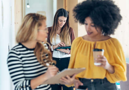 Shot of three smart multiethnic businesswomen working while walking across the hall of coworking place.の写真素材