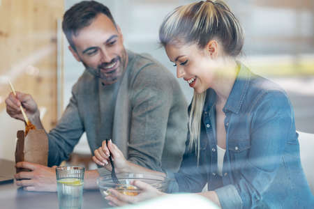 Shot of funny cute multiage couple eating while talking in the kitchen at home.の写真素材