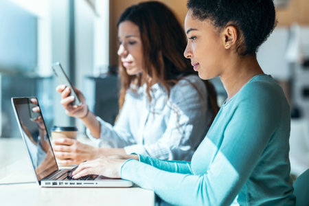 Shot of casual multiethnic business women working with laptops while talking of they new projects...