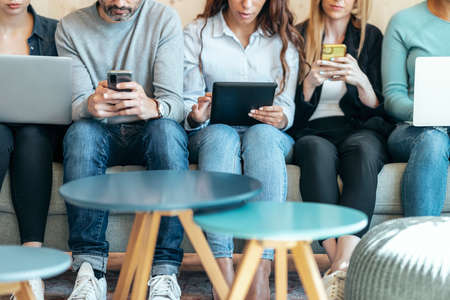 Shot of attractive business people working with her laptop and smartphone sitting together on couch in coworking place.の写真素材
