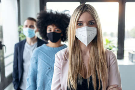 Shot of multiethnic business team wearing a hygienic face mask while looking at camera in the coworking space.の写真素材