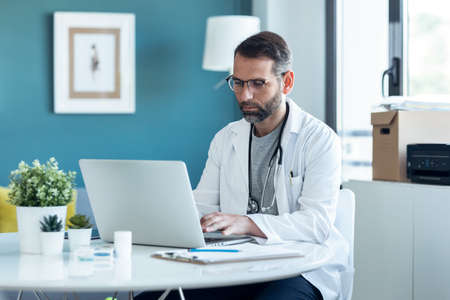 Shot of mature concentrated attractive male doctor working with her computer in medical...