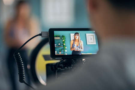 Shot of sporty mature woman blogger shooting fitness workout in the living room at home.