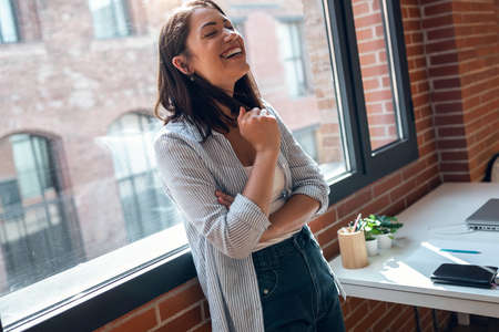 Shot of beautiful young woman smiling while standing in the living room at home.の写真素材