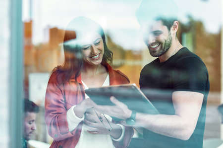 Shot of business team taking a break while cheaking their digital tablet standing in coworking place.の写真素材