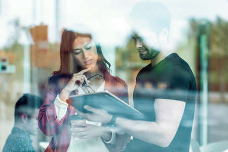 Shot of business team taking a break while cheaking their digital tablet standing in coworking place.の写真素材