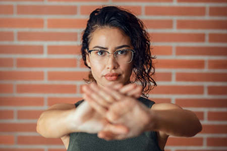 Portrait of fighter woman making stop sign with hands while saying no looking at camera.