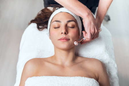 Shot of cosmetologist making face therapy for rejuvenation to woman while lying on a stretcher in...